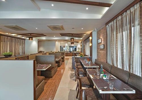 un restaurante con mesas y sofás y un bar en Meritas Crystal Resort, en Lonavala