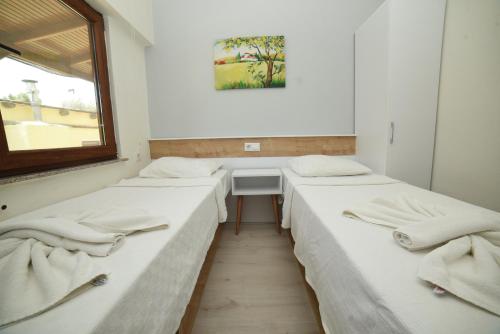 three beds in a room with a window at Limonata Hotel Assos in Behramkale