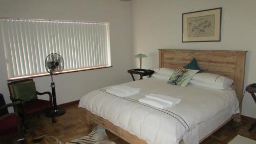 a bedroom with a large white bed with a window at Pinewoods Rest in Somerset West