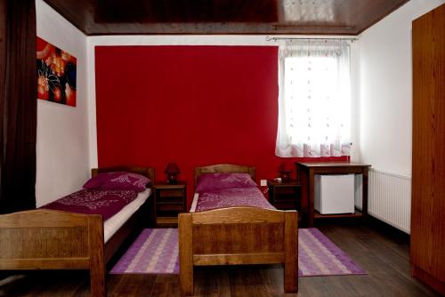 2 camas en una habitación con una pared roja en Guesthouse Pink Panther, en Udbina