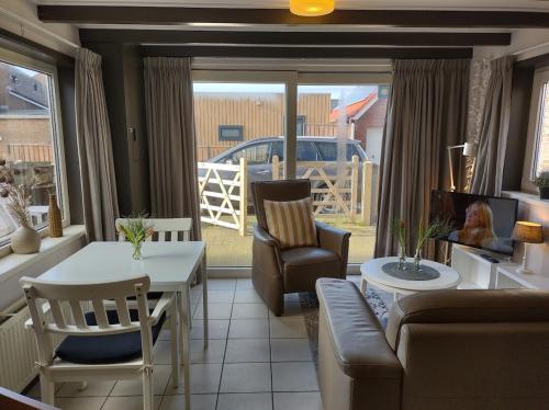 uma sala de estar com um sofá, uma mesa e cadeiras em TINY HOUSE MIMI Bed by the Sea - Adults only em Zoutelande