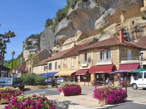 a building with flowers in front of a mountain at La Tuilerie Grange (Adults only gite) with two en-suite double bedrooms in Le Bugue