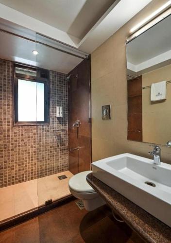 a bathroom with a sink and a toilet and a shower at Meritas Crystal Resort in Lonavala