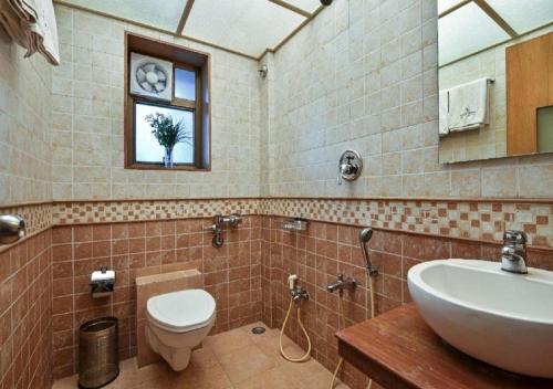 a bathroom with a sink and a toilet and a window at Meritas Crystal Resort in Lonavala