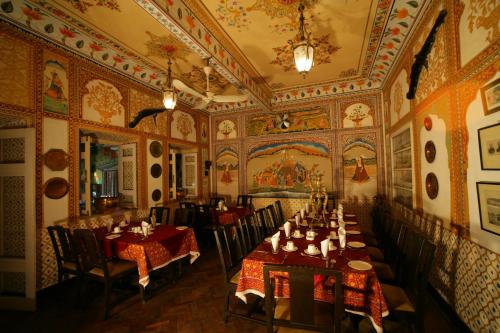 een eetkamer met tafels en stoelen en een plafond bij Hotel Bissau Palace in Jaipur