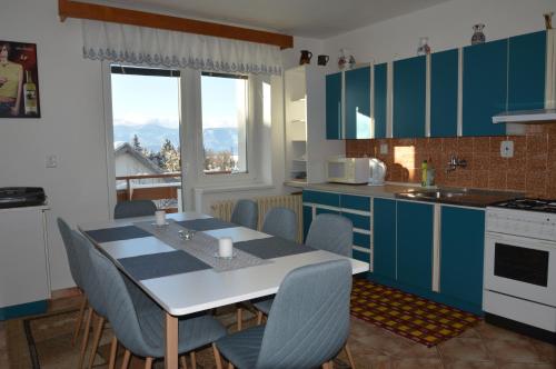 cocina con armarios azules, mesa y sillas en Penzion TOMI en Pribylina