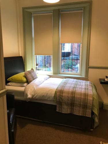1 dormitorio con 1 cama y 2 ventanas en Abberley House, en Carlisle