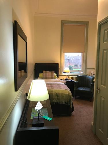 a hotel room with a bed and a table with a lamp at Abberley House in Carlisle