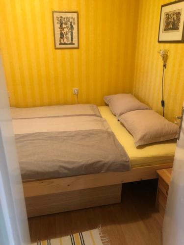 two beds in a room with yellow walls at Örökzöld Apartmanok Balatonfenyves in Balatonfenyves