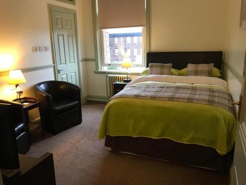 a bedroom with a bed and a chair and a window at Abberley House in Carlisle