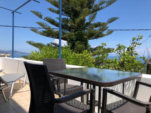una mesa y sillas en un patio con vistas al océano en Villa Thea - Τhe View 1st floor en Áno Yerakaríon