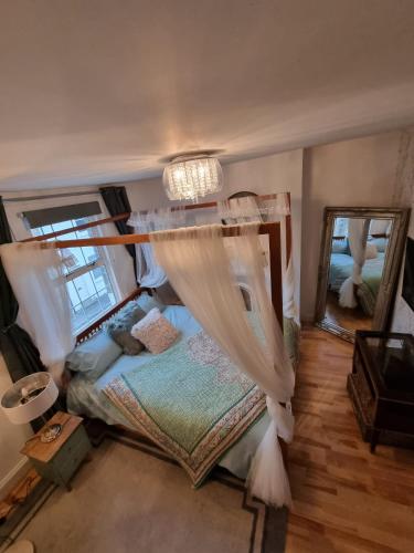 a bedroom with a bed with a canopy and two mirrors at Windsor Retreat in shadow of the Castle. in Windsor
