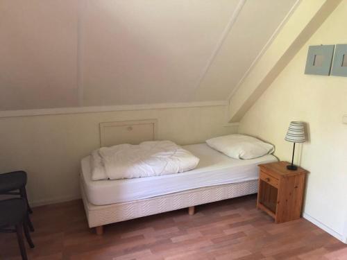 een bed met witte lakens en kussens in een kamer bij Vakantiehuis Kiki in Sondel