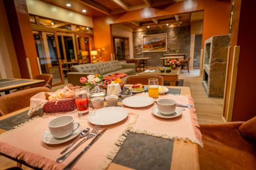 a dining table with plates and utensils on it at Calafate Apart Hotel in Coihaique