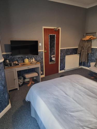 a bedroom with a bed and a desk and a television at Thornhill Blackpool in Blackpool
