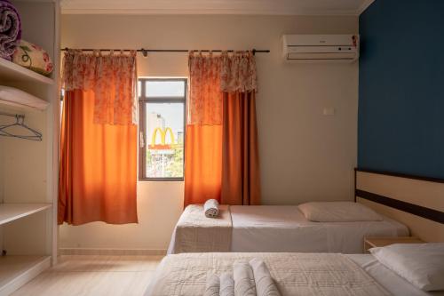 een slaapkamer met 2 bedden en een raam met oranje gordijnen bij Seibt Palace Hotel in Foz do Iguaçu