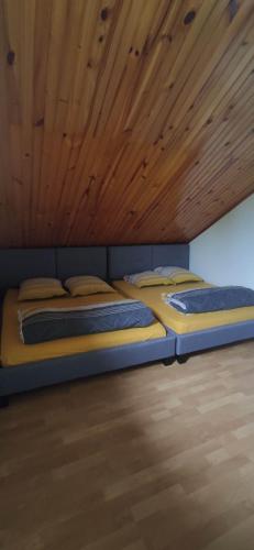 two beds in a room with a wooden ceiling at Gite etape chez Paule et jo in La Possession