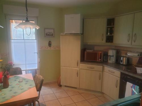 フェルトベルクにあるFerienwohnung Feldberger Seenの白いキャビネットとテーブル付きのキッチンが備わります。