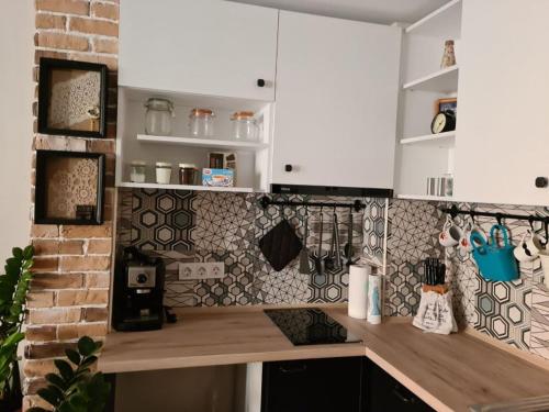 a kitchen with white cabinets and a brick wall at Апартамент (Студио) Тони in Veliko Tŭrnovo