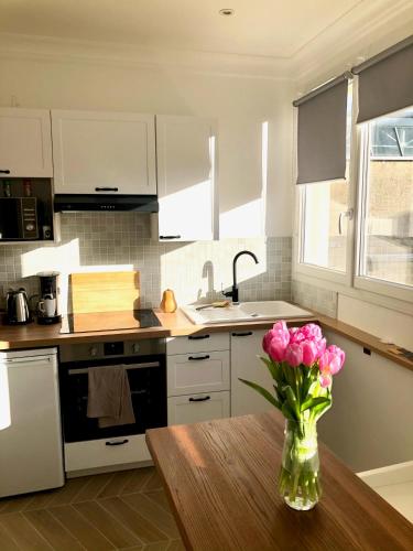 une cuisine avec un vase de fleurs roses sur une table dans l'établissement Bel appartement rénové, centre de Vannes, à Vannes