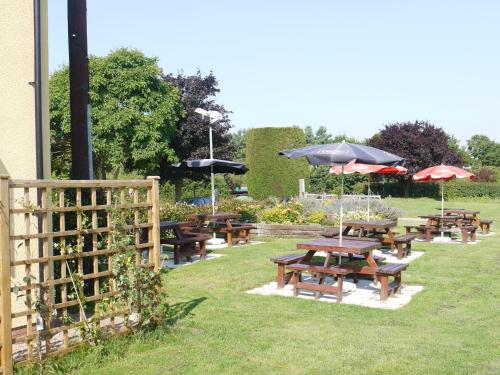 a group of picnic tables with umbrellas and a fence at The New Inn Hotel in Stratford-upon-Avon