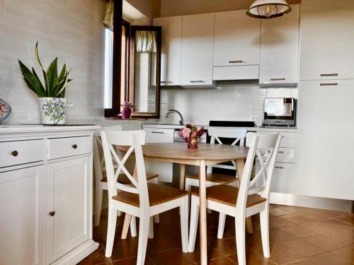 una cucina con tavolo in legno e armadietti bianchi di Salina Holiday Home a Calasetta