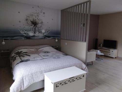 a bedroom with a bed and a table and a television at La Jacarandière in Le Cambout