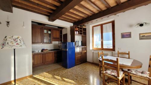 een keuken met een tafel en een blauwe koelkast bij Finestra sulla val d'Orcia in San Quirico dʼOrcia