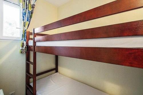 Ce lit superposé en bois se trouve dans un dortoir doté d'une fenêtre. dans l'établissement Bel appartement lumineux à Vieux Boucau avec piscine chauffée - Résidence Domaine du Golf de Pinsolle, à Soustons