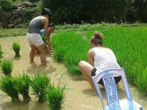 a woman sitting on a chair in the water with a man at Yen Nhi Homestay Ban Gioc in Cao Bằng