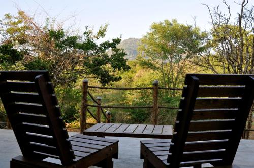 two wooden chairs sitting on a patio with a table at Kele Yala in Yala