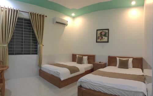 Un dormitorio con dos camas y una ventana. en Khách Sạn Today, en Xã Gia Tân