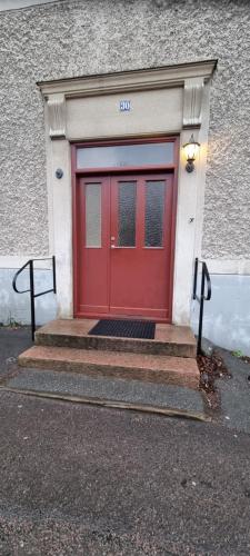 eine rote Tür in einem Gebäude mit einigen Treppen in der Unterkunft Kungsgatan 30 in Åmål