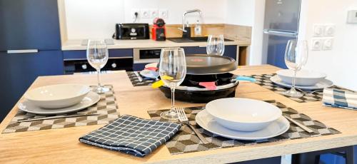 une cuisine avec une table avec des assiettes et des verres à vin dans l'établissement A 2 PAS DU LAC - WIFI - Garage - Netflix - Disney+ - Lac, à Sévrier