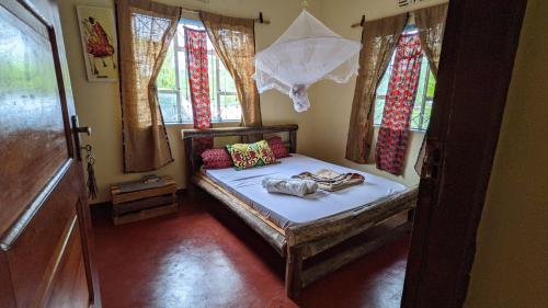 a small bed in a room with windows at Backyard Hostel in Moshi
