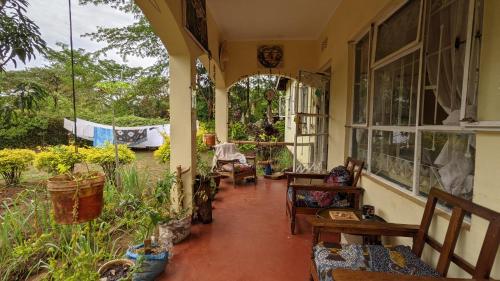 a porch of a house with chairs and windows at Backyard Hostel in Moshi