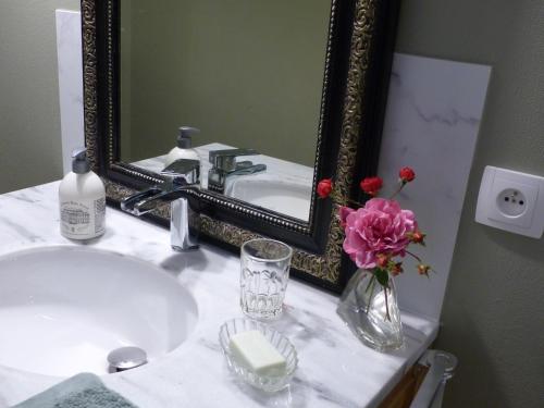 ein Waschbecken mit einem Spiegel und einer Vase aus Blumen in der Unterkunft LE JARDIN DU ROSSIGNOL in Willeman