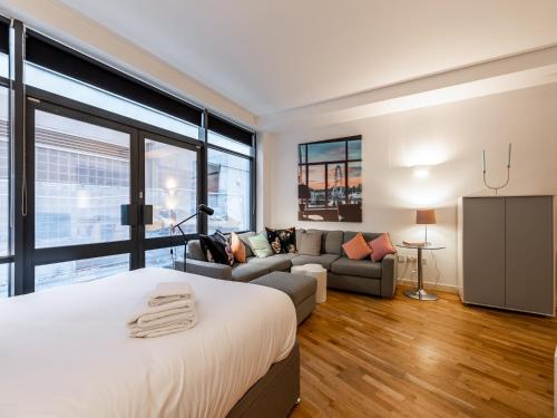 a bedroom with a large bed and a couch at Pass the Keys - Modern Studio Apartment in the heart of Shoreditch in London