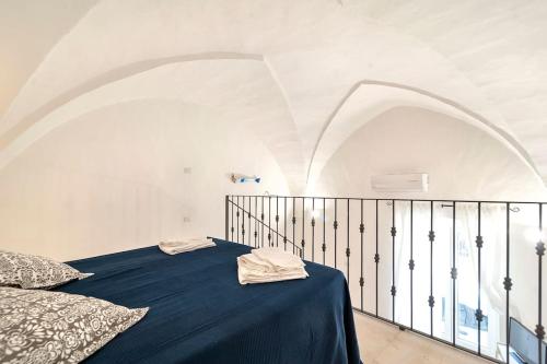 a white room with a bed with a blue blanket at La Dimora della Quercia in Taviano