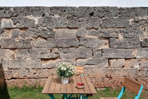 a wooden table with flowers on it next to a brick wall at La Dimora della Quercia in Taviano