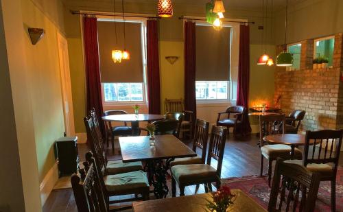 a dining room with tables and chairs and windows at The Kelvin Hotel in Oban
