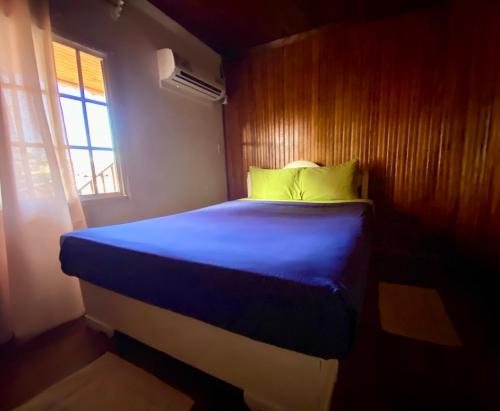 a bedroom with a blue bed with a wooden wall at Cat in The Cup B&B in Bocas del Toro