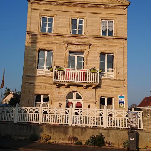 a building with a balcony with an american flag on it at JOYEUX REVEIL in Courseulles-sur-Mer