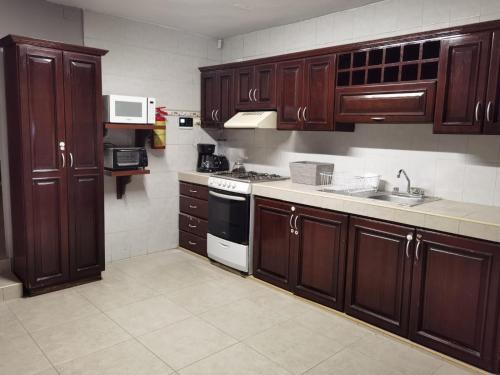 Una cocina con gabinetes de madera y un horno de estufa. en Casa Buba, en Cozumel