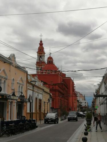 a red building with a clock tower on a city street at Departamento Caseros in Salta