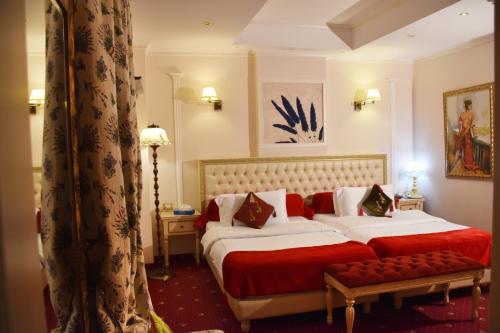 a bedroom with a large bed with a red blanket at 2 KITARRAT Boutique Hotel & SPA in Durrës