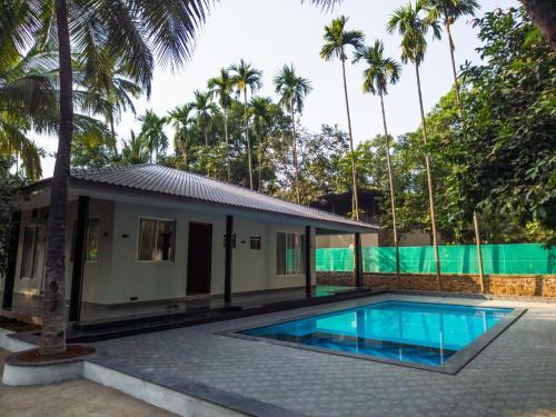 uma villa com piscina em frente a uma casa em Shiny 2Bhk Alibaug em Alibaug