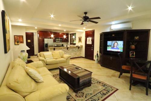 a living room with a couch and a tv at Monte Carlo Luxury Condominiums in Jacó