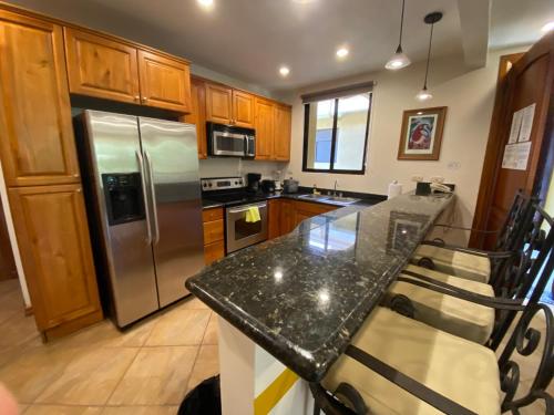a kitchen with a granite counter top and stainless steel refrigerator at Monte Carlo Luxury Condominiums in Jacó