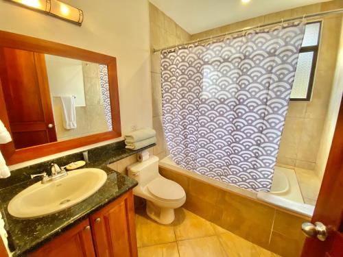 a bathroom with a sink and a shower curtain at Monte Carlo Luxury Condominiums in Jacó